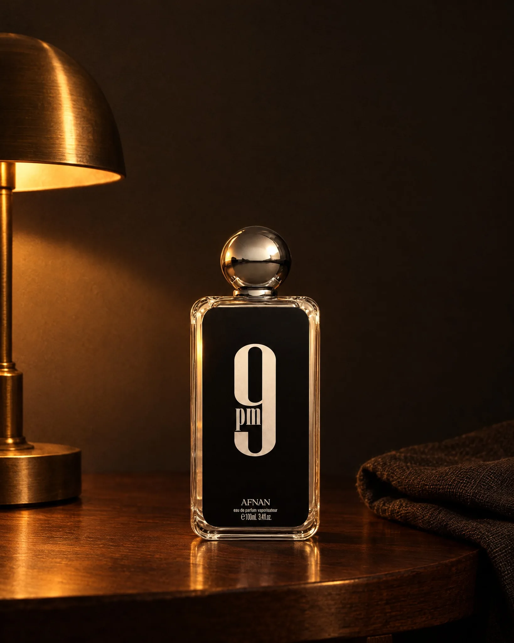 Afnan 9PM bottle on a dark wooden side table under a brass lamp